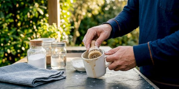 Hands cleaning coffee stains with baking soda paste in mug